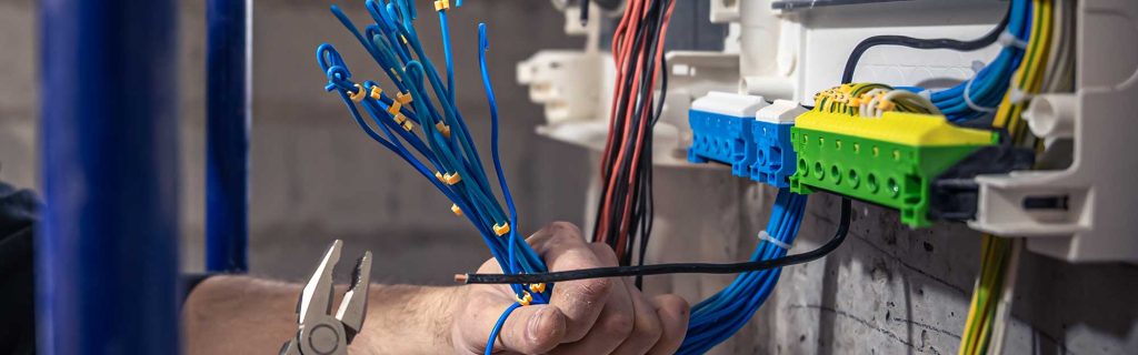 A service electrician wearing protective gear while working on electrical wiring