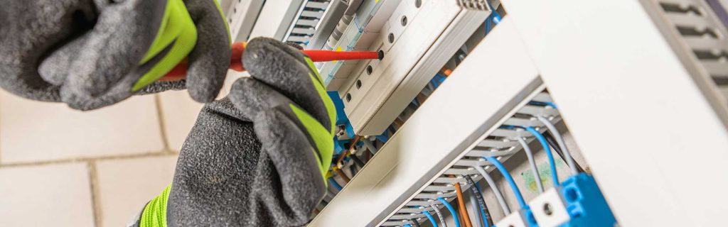 An expert electrician installing an electrical panel in a commercial building, highlighting expertise in commercial electrical services